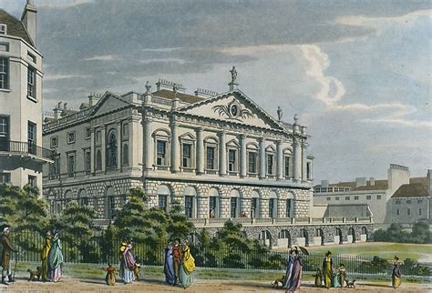 an old building with many people walking around in front of it and on the other side