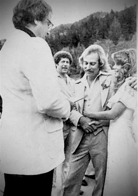 an old black and white photo of two men shaking hands with other people in the background