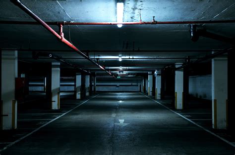 An underground empty urban industrial dark parking lot with fluorescent ...