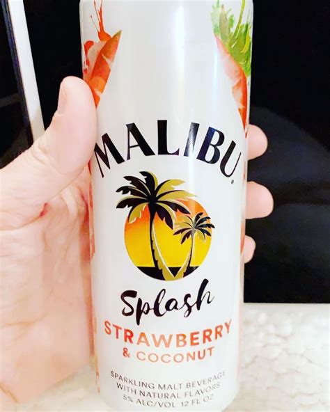 a hand holding a bottle of malubu splash strawberry and coconut drink ...