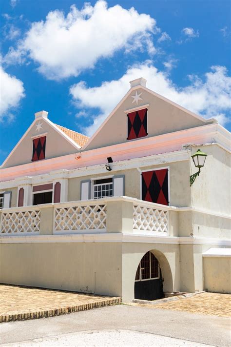 a large white building with red shutters under a blue sky