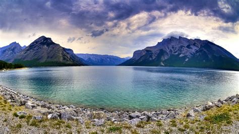 River Surrounded By Stones Trees And Mountains Under Blue Cloudy Sky ...