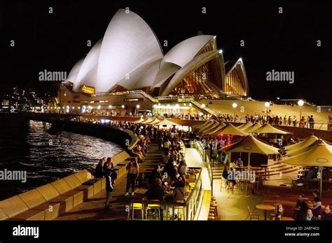 Sydney Opera House and sydney harbour at night - bars busy with people enjoying the nightlife ...