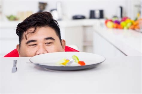 Premium Photo | Overweight man peeking out salad of the table