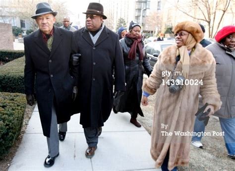 two men in coats and hats are walking down the sidewalk with other ...