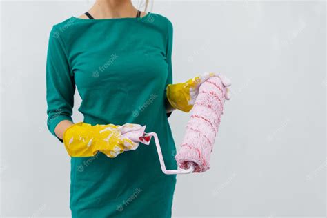 Premium Photo | A young girl stands with a pink roller in her hands against a white wall in a ...