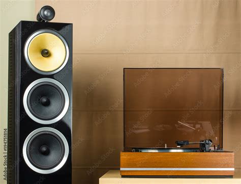 Vintage turntable playing a vinyl record and modern black speakers ...