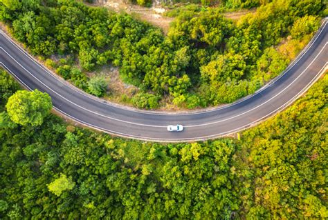 Aerial view of road with car in beautiful forest in summer Stock Photo by den-belitsky