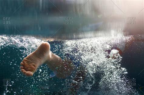 Underwater view of child's feet kicking stock photo - OFFSET