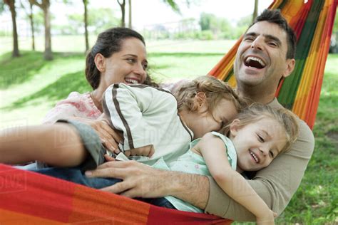 Family laughing together on hammock - Stock Photo - Dissolve