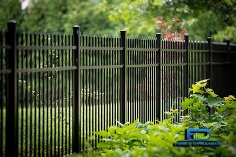 a black metal fence in the middle of some green plants