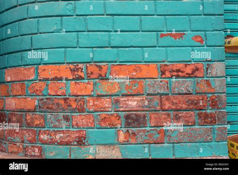 Colourful wall surface with exposed bricks texture and turquoise paint. Urban details for ...