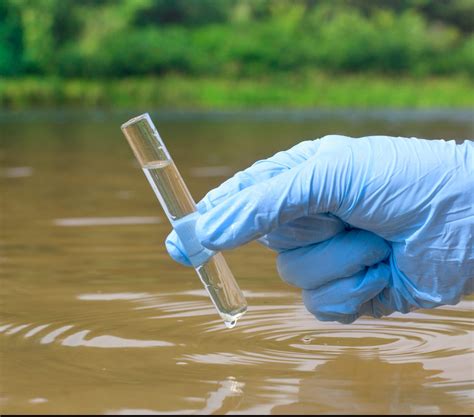 Sample water from the river for analysis. Hand in glove holding - Mantech