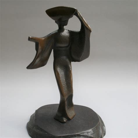 A cast iron sculpture of a geisha in a hat and flowing dress