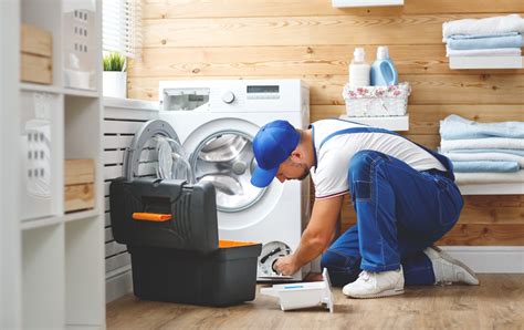 working man plumber repairs washing machine in laundry - EVS