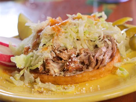 a yellow plate topped with meat and coleslaw next to an onion wedged apple