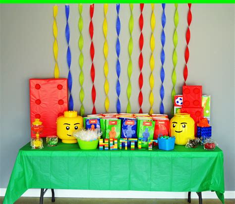 a green table topped with lots of legos and candy bar decorations on top of it