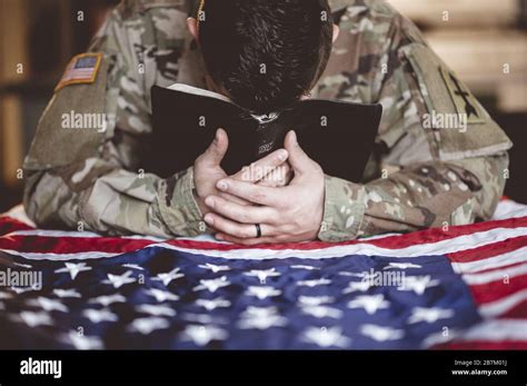 American soldier mourning and praying with the Bible and the American flag in his hands Stock ...
