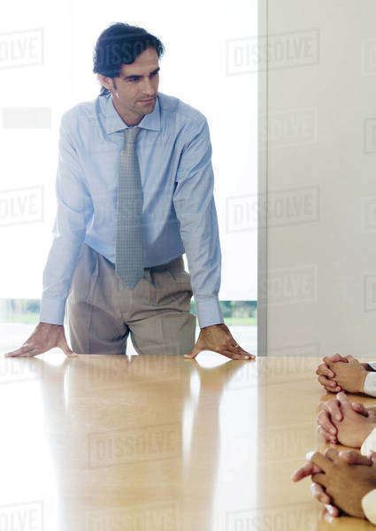 Businessman standing with hands on table during meeting - Stock Photo - Dissolve