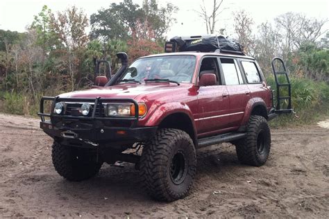 a red four wheel drive vehicle parked in the mud