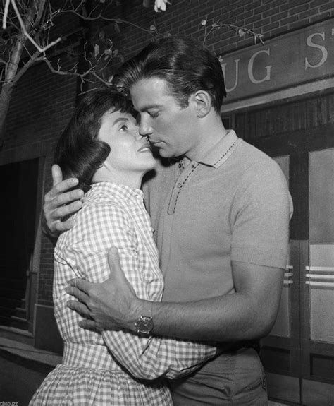 a man and woman embracing each other in front of a brick building with ...