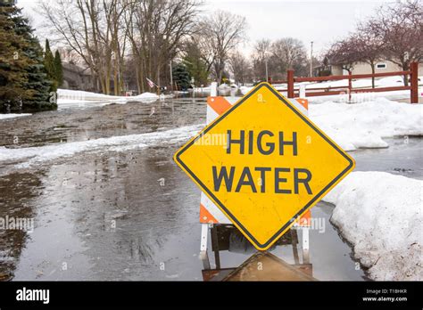 A high water sign is sitting in a flooded street after a heavy rain and ...