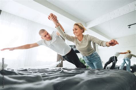 Young happy couple jumping on bed and make fun while sitting at home ...