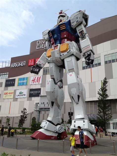 a giant robot statue in front of a building with people standing around ...