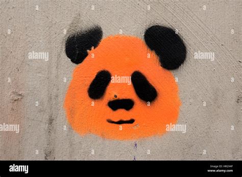 Arte de la calle graffiti en una pared gris que representa el rostro de un panda gigante naranja ...