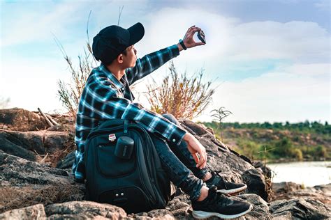 Focused young Asian man examining stone while sitting by river · Free Stock Photo