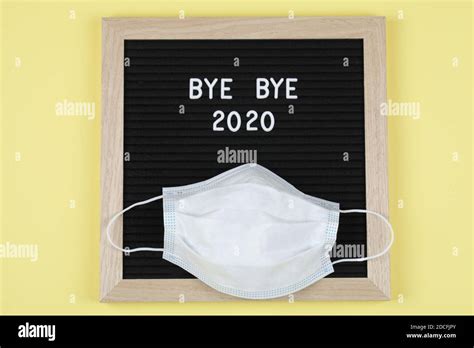 black letter board with text BYE BYE 2020 with mask on yellow background. . Top view. flat lay ...