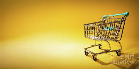 Shopping cart on yellow background in spotlight Photograph by Michal Bednarek - Fine Art America