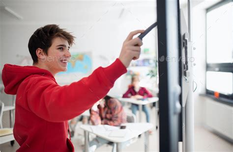 College student explaining some ideas on a touch TV in classroom. Stock Photo by halfpoint