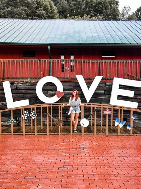 a woman standing in front of a love sign on the side of a wooden building