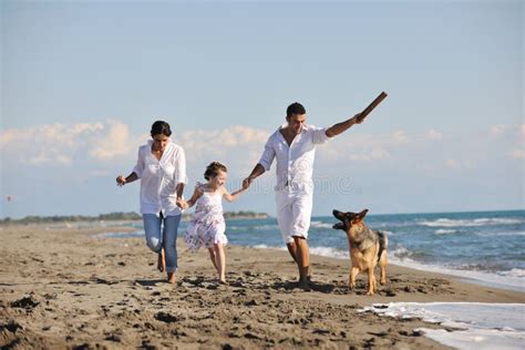 Familia Feliz Que Juega Con El Perro En La Playa Imagen de archivo - Imagen de muchacha ...