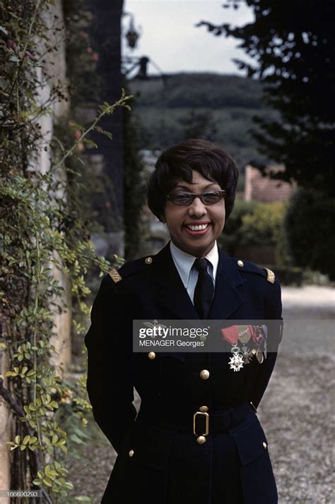 a woman in uniform standing next to a wall with ivy growing on it and ...