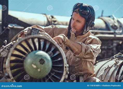 Portrait of a Mechanic in Uniform and Flying Helmet, Repairing the Dismantled Airplane Turbine ...