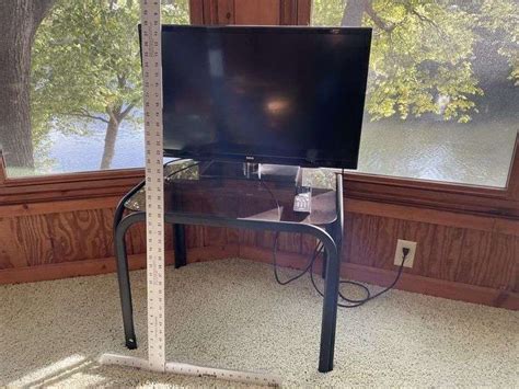 Glass top table and RCA 32 inch TV with remote - Legacy Auction Company