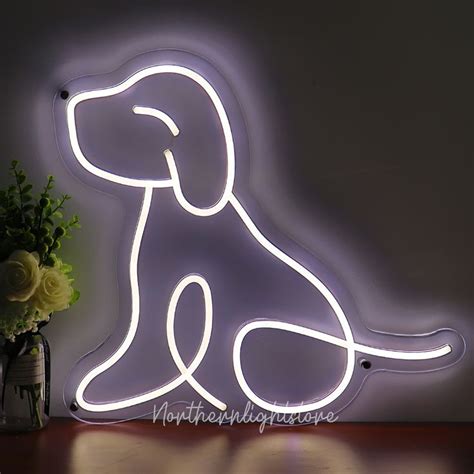 a neon dog sign sitting on top of a table next to a vase with flowers