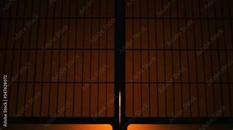 Silhouette behind sliding paper doors with lamp yellow backlight opening door and man entering ...