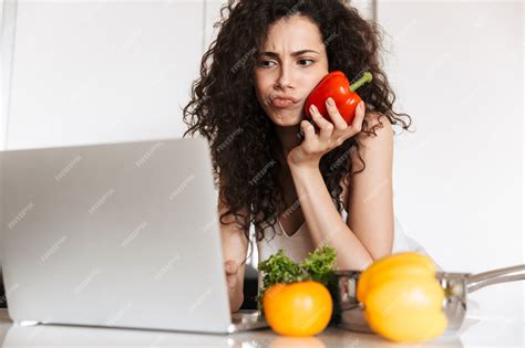 Premium Photo | Serious curly woman 20s holding sweet paper and reading recipe from laptop ...