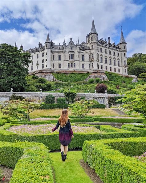 a woman walking through a maze in front of a castle