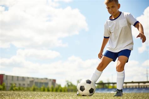 Bonito garoto de um ano de idade jogando futebol com uma bola na grama ...