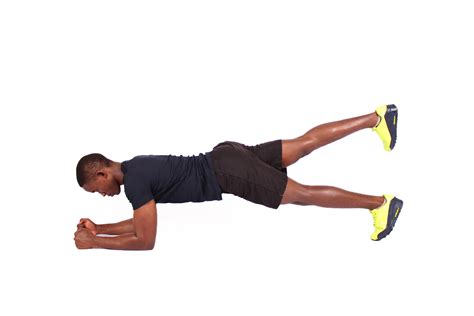 Young man doing front plank raising one leg