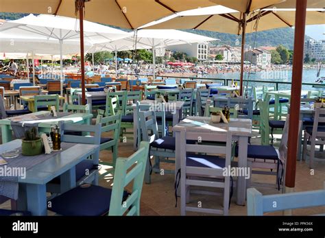 Empty chairs and tables in Petrovac restaurant in daytime. Beach and hotels in the background ...