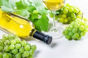 Wine background with ripe fresh grapes, full bottle and glass and green branches with leaves ...