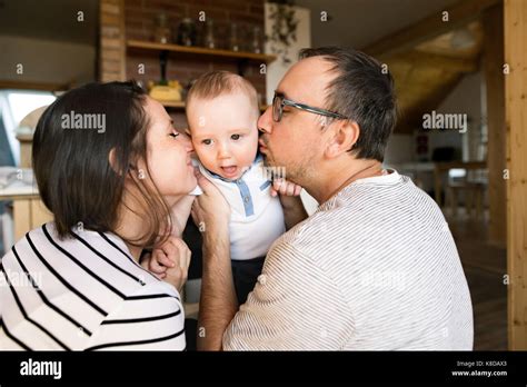 Beautiful young parents kissing their cute baby son Stock Photo - Alamy