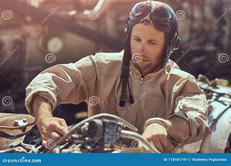 Portrait of a Mechanic in Uniform and Flying Helmet, Repairing the Dismantled Airplane Turbine ...