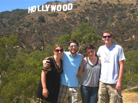 three people standing in front of the hollywood sign with trees and ...