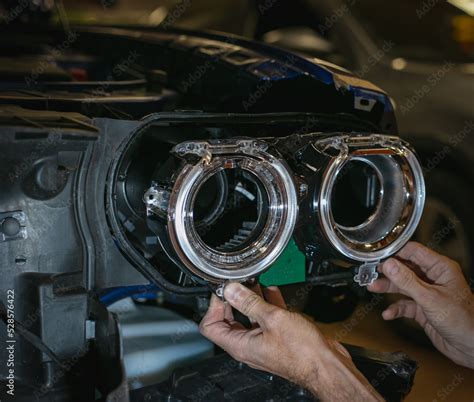 Car headlight in repair close-up. The car mechanic installs the lens in ...